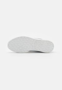 Fehér sneaker talp textúrázott, mintázott felülettel. Kör alakú díszítéssel és háromszögletű barázdákkal rendelkezik a tapadás érdekében.