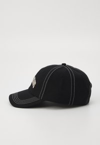 Black cotton baseball cap with white stitching, curved peak, embroidered logo on front, and ventilation eyelets at the crown.