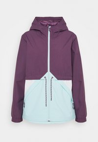 Chaqueta de estilo masculino que presenta una parte superior morada, secciones inferiores turquesa, cordones ajustables y un frente con cremallera falsa.