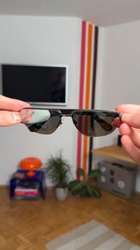 Mustad päikeseprillid terava nurga kujundusega. Tumedad läätsed, metallraam hõbedaste detailidega. Ilma nähtavate logode või mustriteta.