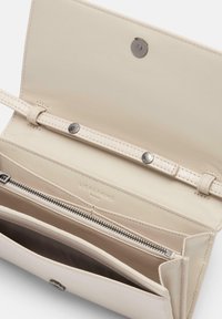 Portafoglio in pelle crema con una texture liscia, tasca con zip, chiusura a bottone e più scomparti per carte. Logo impresso visibile all'interno.