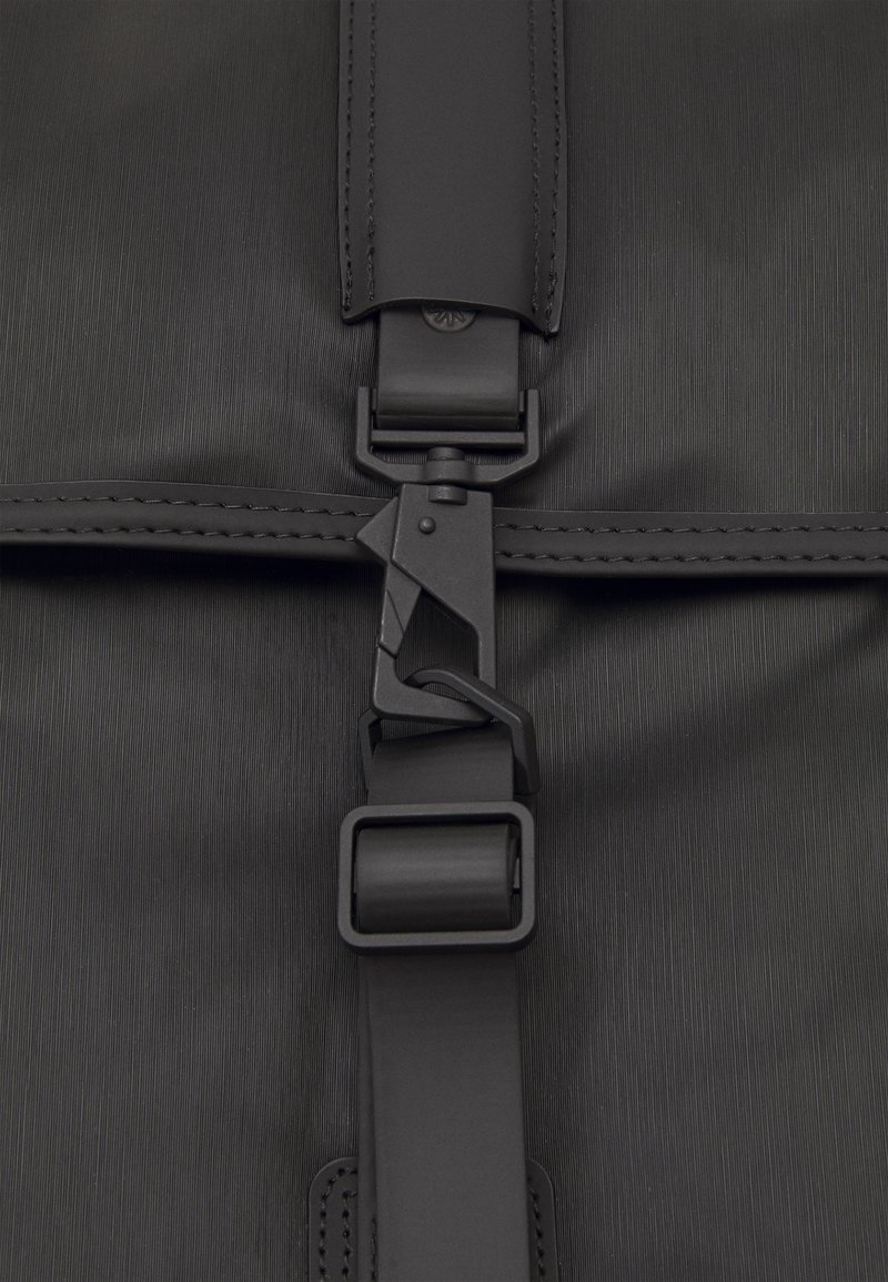 Spallacci di zaino in tessuto nero con chiusura a clip in plastica e cuciture eleganti, con superficie testurizzata e un sottile motivo a righe.