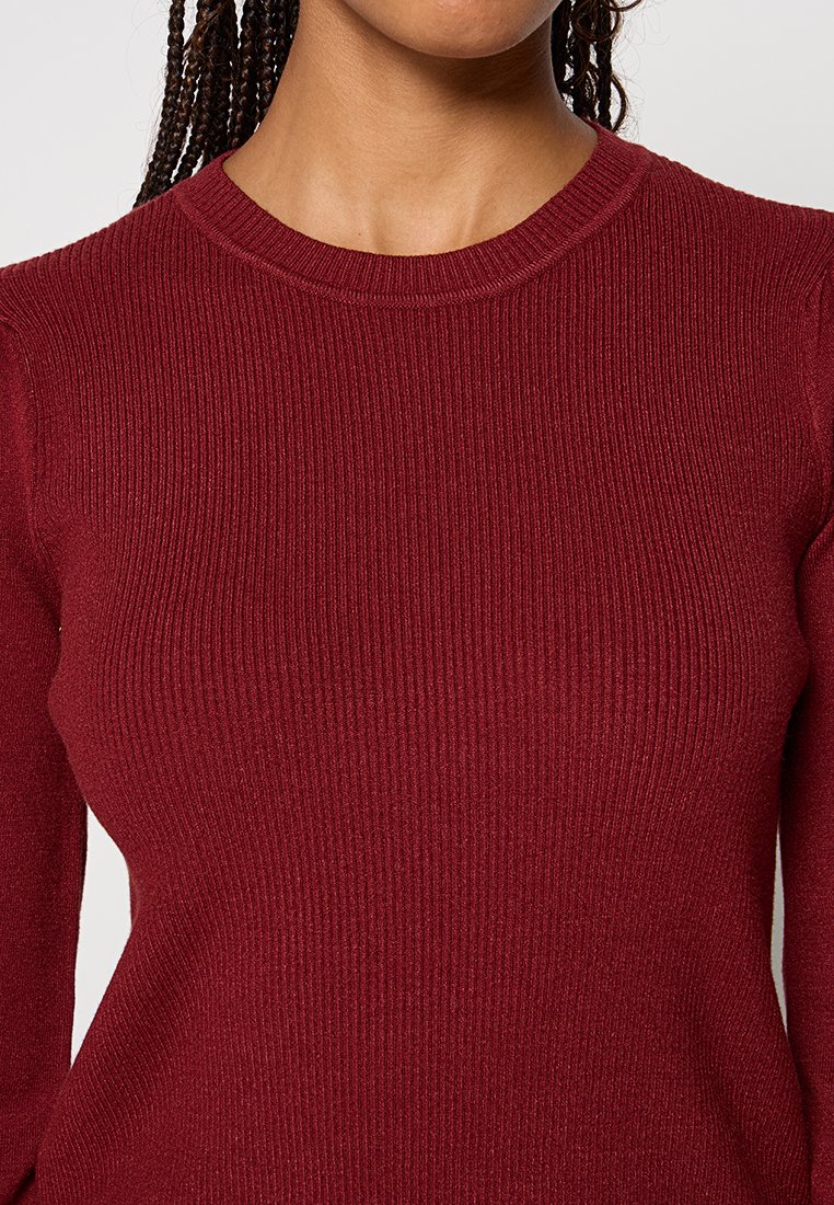 Bordeaux geribbelde trui met lange mouwen en een ronde hals; gemaakt van zacht gebreid materiaal met een subtiele textuur.