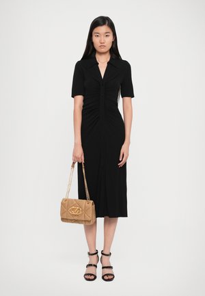 Schwarzes, kurzärmliges Kleid mit Knopfverschluss und gerafftem Muster. Kombiniert mit einer tanfarbene, gesteppten Handtasche und Sandalen mit Absatz.