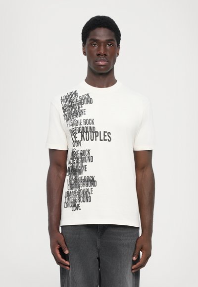 T-shirt a maniche corte, collo rotondo, in cotone crema con un design testuale nero a contrasto che presenta diverse parole disposte verticalmente su un lato.
