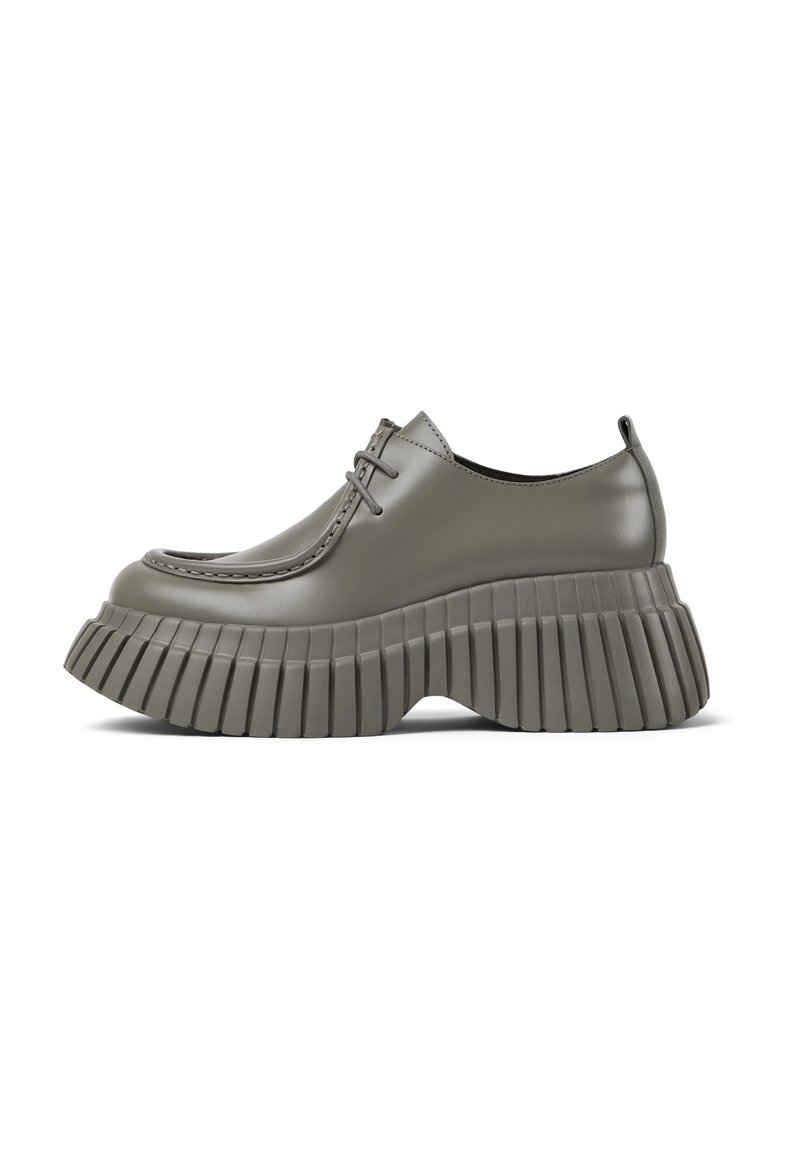 Chaussures grises élégantes avec un dessus lisse et une semelle prononcée et striée. Le design présente un laçage et une esthétique contemporaine.