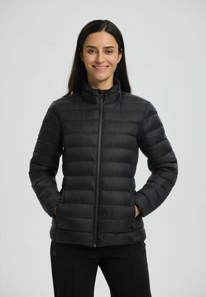 Zwarte pufferjack met een hoge kraag, gewatteerd ontwerp, rits aan de voorkant en zijzakken. Lichtgewicht materiaal met een gladde textuur.