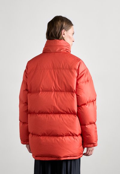 Rode pufferjack met een hoge, gewatteerde kraag, gelaagde ontwerp en zichtbare stiksels. Glad textuur met een losse pasvorm, achterstevoren gedragen.