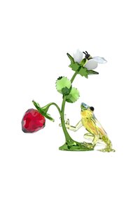 Figurina di cristallo con uno stelo verde, un fiore bianco e una fragola rossa, accompagnata da una rana giallo-verde con dettagliate sfaccettature.