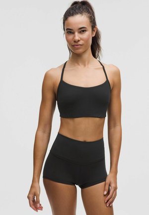 Top corto atlético negro con tirantes finos y pantalones cortos de cintura alta a juego, hecho de un tejido liso y elástico. Diseño simple, sin patrones.