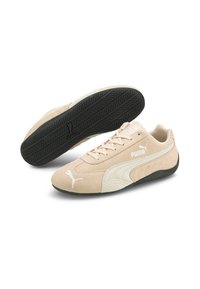 Baskets Puma avec une tige en daim beige agrémentée d'accents blancs, une semelle extérieure en caoutchouc noire texturée et un design à bout arrondi.