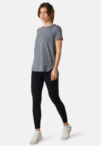 Gray, short-sleeve t-shirt with a subtle heather texture, paired with black leggings and white athletic shoes, showcased in a standing pose.