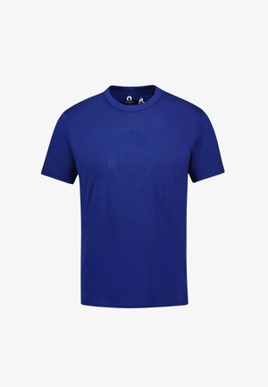 T-shirt di cotone blu con scollo rotondo, con un logo in rilievo delle Olimpiadi Parigi 2024 sul davanti. Maniche corte, tinta unita.