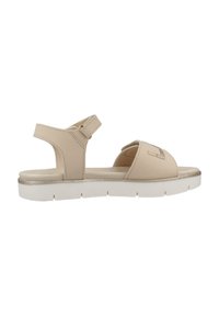 Beige sandalen met verstelbare enkelband, zacht materiaal, open teen ontwerp en een witte rubberen zool met een metallic accent.