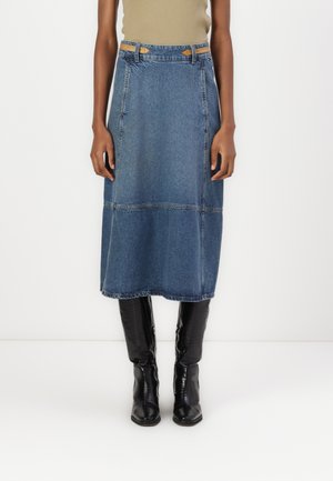 Denim midi-skjørt med rett snitt, lyseblå farge og kontrastsøm. Har belte i midjen med brune detaljer. Brukt med svarte støvler.