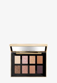 Palett med åtte firkantede øyenskygger: to matte, fire shimmer, og to glitrende, i nøytrale toner og et lokk med gullspeilfinish.
