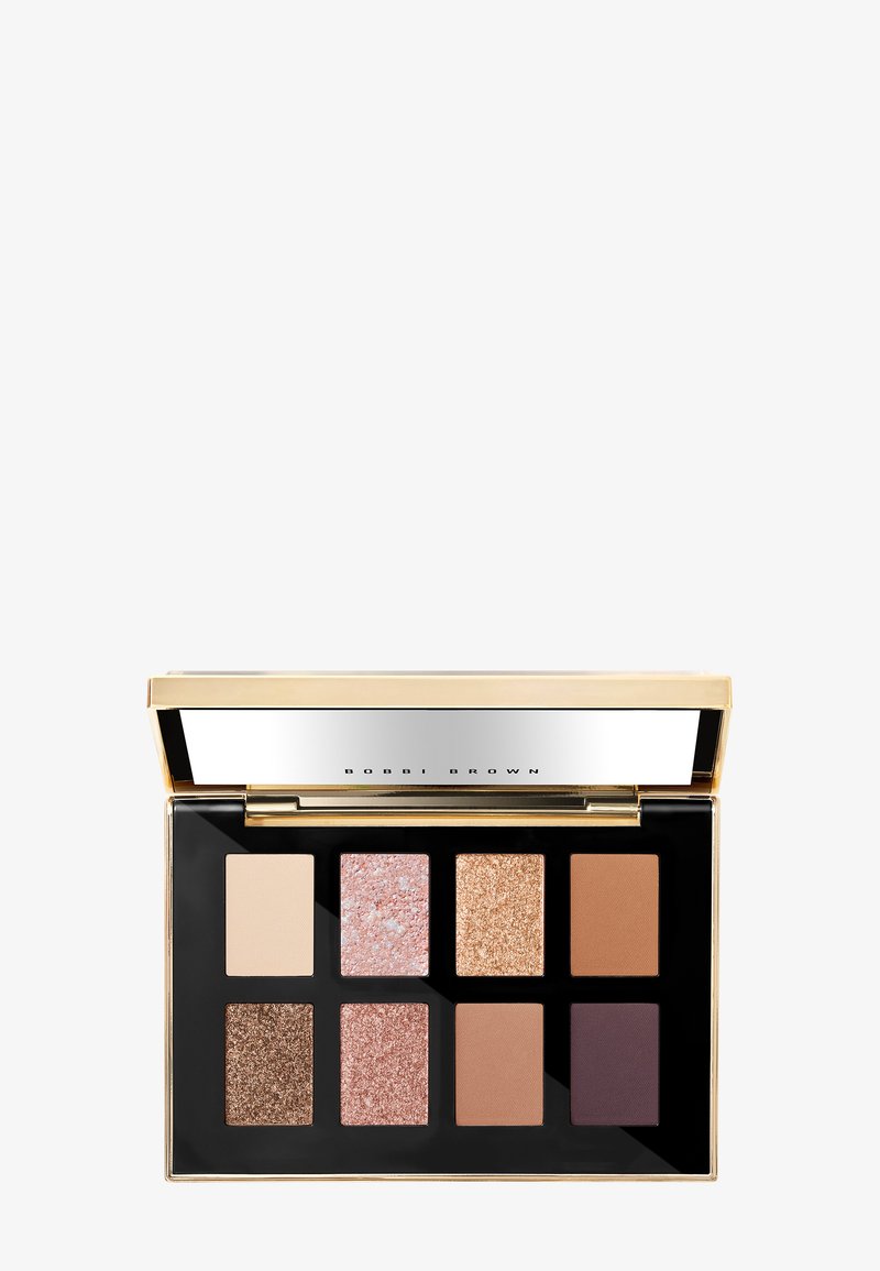 Palett med åtte firkantede øyenskygger: to matte, fire shimmer, og to glitrende, i nøytrale toner og et lokk med gullspeilfinish.