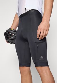 Pantaloni ciclistici neri con una superficie liscia, caratterizzati da una vestibilità aderente, una tasca con zip sul lato e dettagli del logo sulla gamba sinistra.
