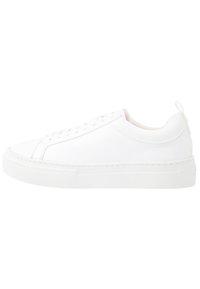 Vita lädersneaker med rund tå, platta snören och en texturerad gummisula. Har en minimalistisk design och subtila sömnadsdetaljer.