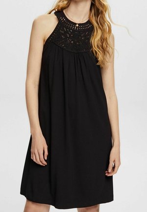 Zwarte jurk met halternek en kantdetails op het lijfje. Zachte stof, losse pasvorm en knielengte ontwerp.