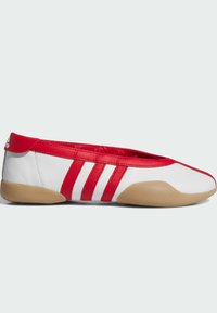Bijele i crvene ravne kožne cipele s gumenim potplatom, s tri crvena pruga i glatkim, zaobljenim vrhom. Minimalistički dizajn, bez vidljivih uzoraka.