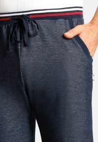 Türkise Strick-Jogginghosen aus strukturiertem Stoff, mit einem kontrastierenden gestreiften Bündchen in Rot und Weiß sowie Seitentaschen für Stauraum.