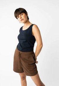 Marineblaues Tanktop mit Rundhalsausschnitt, kombiniert mit braunen Shorts mit Kordelzug und seitlichen Taschen, gefertigt aus weichem, leichtem Stoff.