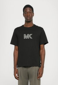 Čierne bavlnené tričko s geometrickým bielym logom "MK" na hrudi. Krátke rukávy a dizajn s okrúhlym výstrihom.