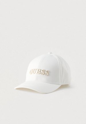 Casquette blanche en tissu. Présente une couronne arrondie et une visière incurvée. "GUESS" brodé en beige sur le devant. Design simple, sans motifs.
