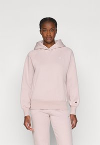 Hoodie rose clair en tissu doux, avec une poche kangourou, des poignets côtelés et un logo sur la poitrine et la manche.