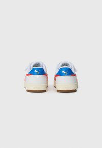 Baskets rouges et bleues avec des accents blancs. Matériau texturé, lacets blancs plats, semelle en gomme et détail doré du logo sur le talon.