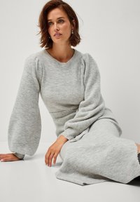 Abito maglione grigio a maglia oversize con maniche lunghe e gonfie e texture a coste. Affiancato in vita, con una gonna leggermente ampia e svasata.