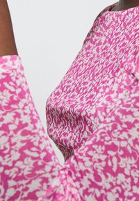 Kortärmad topp i rosa tyg med ett blommönster, slät textur och avslappnad passform med rund halsringning.