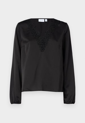 Must mustustega V-kaelusega bluus, millel on keerukas musta värvi lilleline tikand. Sile sätendav tekstuur ja elastsed mansetid.