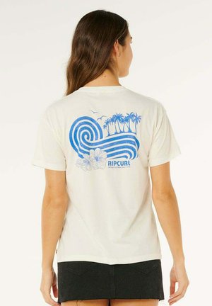 Femme portant un t-shirt blanc avec un motif de vague bleue, palmiers, fleurs et oiseaux, et le texte « RIP CURL » au dos.