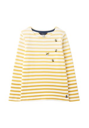 Żółto-biała koszula w paski z długim rękawem, z haftowanymi pszczołami na piersi i małym czarnym logo królika blisko dołu.