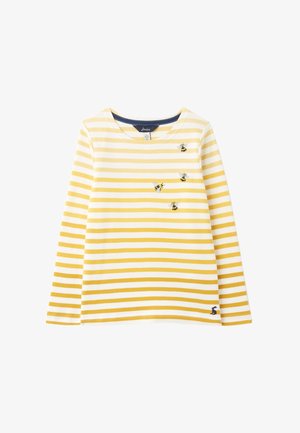 Żółto-biała koszula w paski z długim rękawem, z haftowanymi pszczołami na piersi i małym czarnym logo królika blisko dołu.