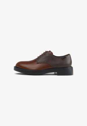 Zapato de hombre de piel marrón bicolor con cordones, suela negra y tacón bajo, mostrado de perfil sobre fondo blanco.