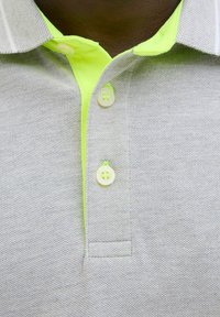 Graues Poloshirt aus strukturiertem Stoff, mit einem neongrünen Kragen und subtilen gestreiften Akzenten. Drei weiße Knöpfe zieren die Knopfleiste.