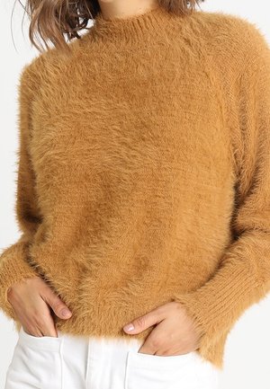 Puszysty sweter w kolorze musztardowym z okrągłym dekoltem, prążkowanymi mankietami i dołem. Teksturowany materiał o miękkim wykończeniu. Dopasowany fason.