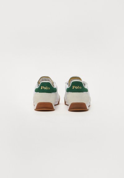 Tênis brancos com detalhes verdes, calcanhar em camurça e o logótipo dourado "Polo". Apresenta uma sola de borracha castanha com o branding em relevo "Ralph Lauren".