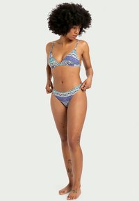 Bikini set koji se sastoji od trokutaste gornje strane i donjih hlačica niskog struka, izrađen od tkanine s plavim i zelenim geometrijskim uzorkom, s glatkom teksturom.