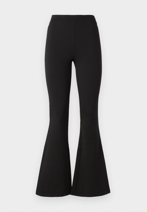 Schwarze, ausgestellte Leggings aus dehnbarem Material, mit einem hohen Taillenbund und einer glatten Textur, die sich bis zu einem weiten Saum an den Knöcheln verjüngen.