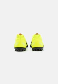 Scarpe da calcio con una parte superiore sintetica gialla brillante, suola in gomma nera e dettagli riflettenti. Progettate per aderenza e stabilità.