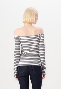 Valge off-the-shoulder pikkade varrukatega topp, millel on tumesinised triibud, ribakujuline tekstuur, sobiva disainiga ja sujuva pinnaga.