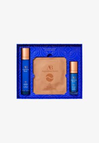 Skincare gift set featuring two blue bottles with orange caps, a gold eye patch packet, all in a navy box with floral patterns.