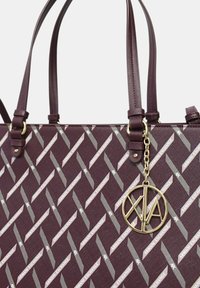 Borsa a spalla borgogna con un motivo geometrico e dettagli in argento. Presenta manici doppi e un charm con logo dorato attaccato tramite una catena.