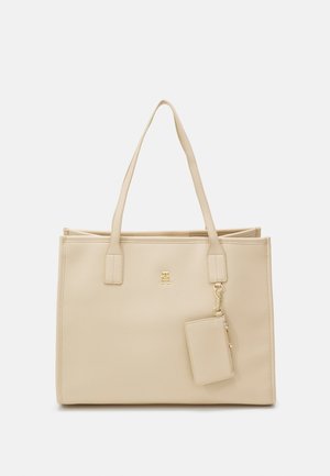 Sac fourre-tout beige avec deux poignées, fabriqué dans un matériau lisse. Il présente un logo doré et un portefeuille détachable avec fermeture éclair. Forme rectangulaire simple.