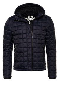 Laivastonsininen tikattu takki hupulla, jossa on vetoketju edessä, kaksi sivutaskua ja joustavat hihansuut. Materiaali vaikuttaa sileältä ja synteettiseltä.