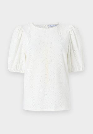 Balta blūze ar pūkainām piedurknēm, apaļu kakla izgriezumu un acs rakstu tekstūrai. Aizmugurējā atslēgas formas aizdare piešķir smalku dizaina elementu.